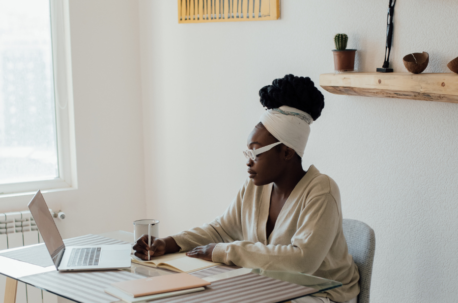 Black woman wearing glasses working from home at a desk in front of her laptop.