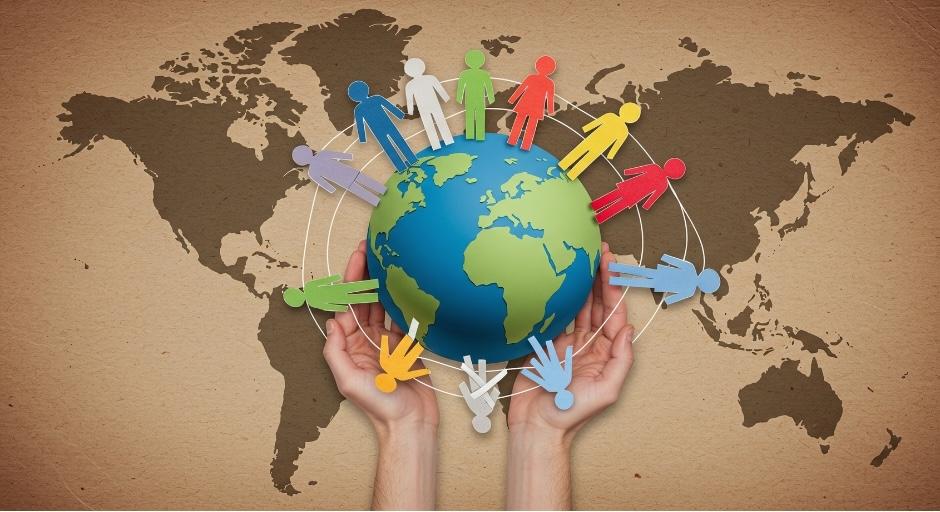 A brown world map background with two hands holding a World Globe on top. The globe is surrounded by a ring of colorful paper-cut out people.