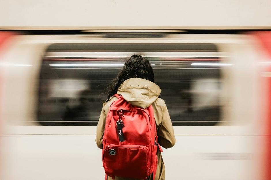 Female worker standing with her back to us looking at the London underground public transport for her work commute.