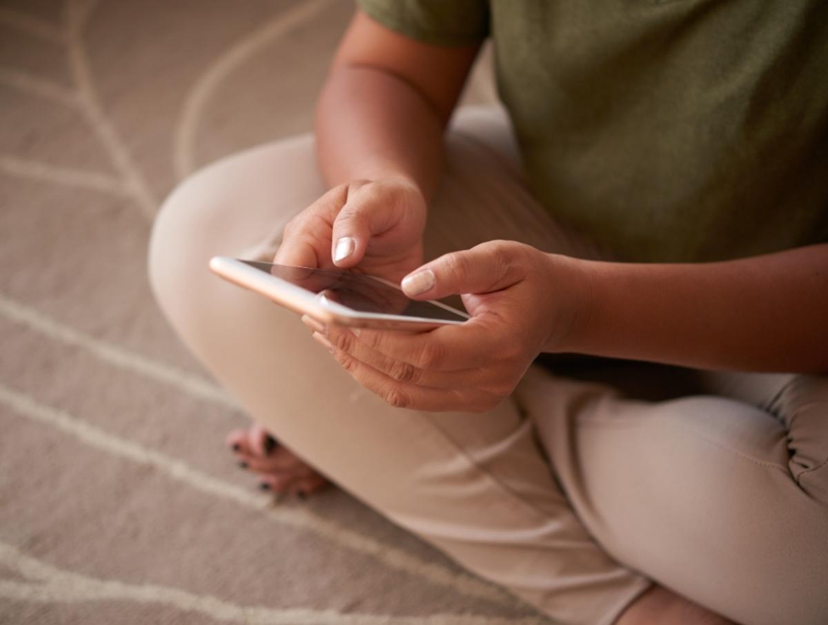 Woman sat crossed-legged using mobile phone - Wysa JMIR