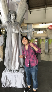 Real wysa user smiling next to a statute holding up a peace sign with her left hand.