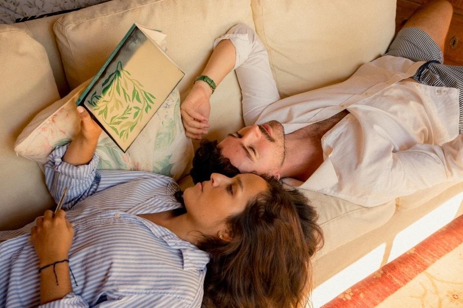 Couple laying on the sofa together, top and tale, reading a book during covid lockdown.
