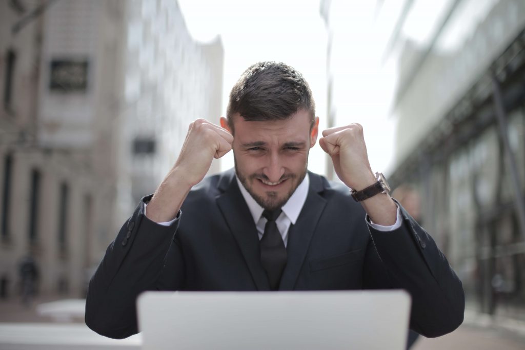 A man looking at his laptop with an expression of excitement
