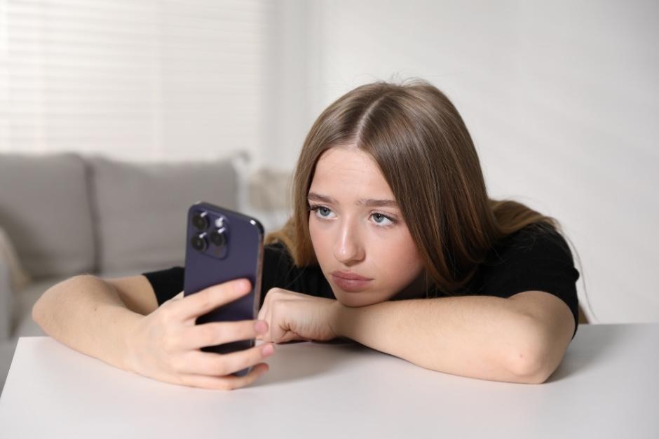 Teenage girl with chin lowered looking deflated at her phone.